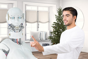 A man pointing at a robot in a living room