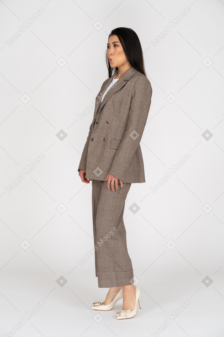 茶色のビジネススーツを着たふくれっ面の若い女性の4分の3のビュー