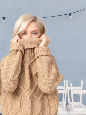 A woman in a beige sweater covering her face