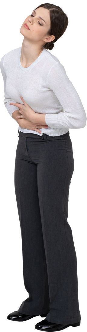 Vista di tre quarti di una giovane donna in abiti da ufficio che tocca lo stomaco