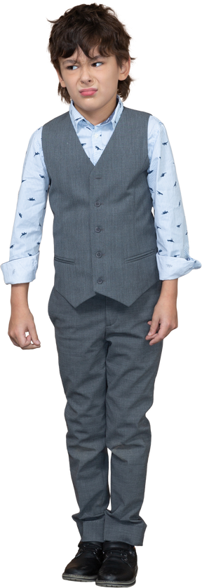 Vista frontal de un niño enojado en traje gris parado