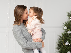 A woman holding a small child near a christmas tree