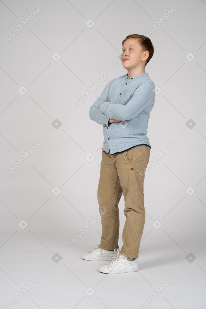 Niño posando con los brazos cruzados y mirando hacia arriba