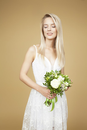 Schöne junge braut, die blumenstrauß von weißen blumen hält