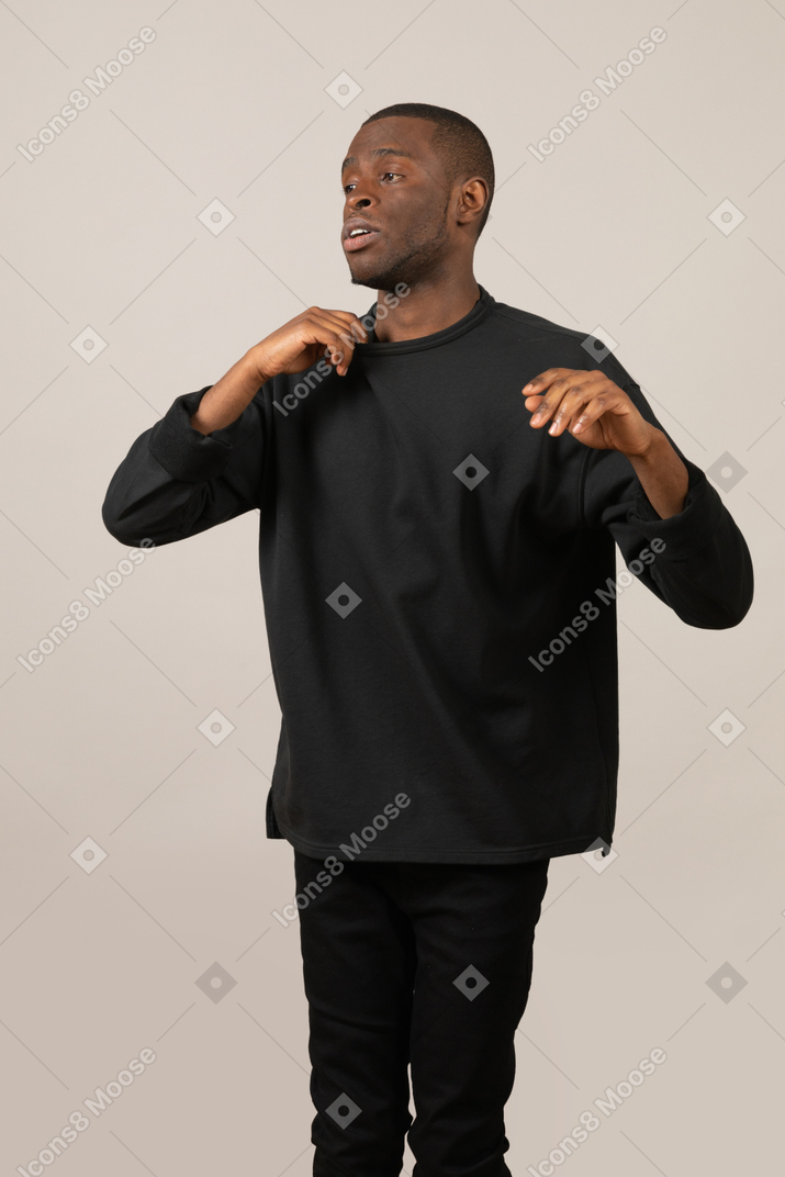 Young man pulling crewneck collar and looking aside