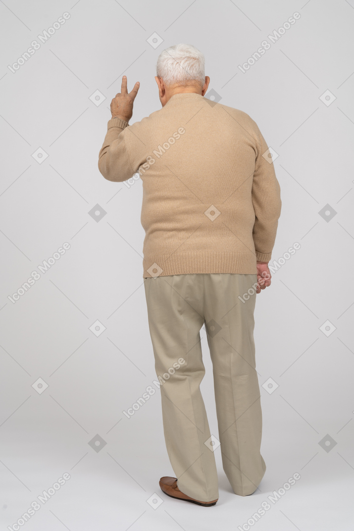 Vista posteriore di un uomo anziano in abiti casual che mostra il segno v