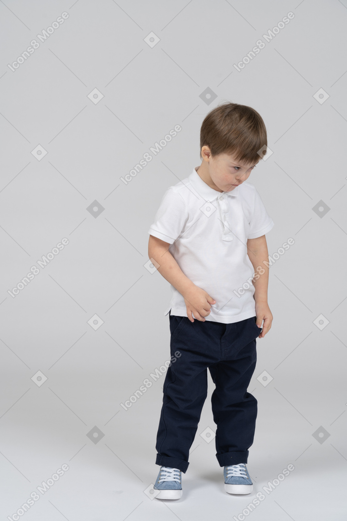 Little boy standing with his head down