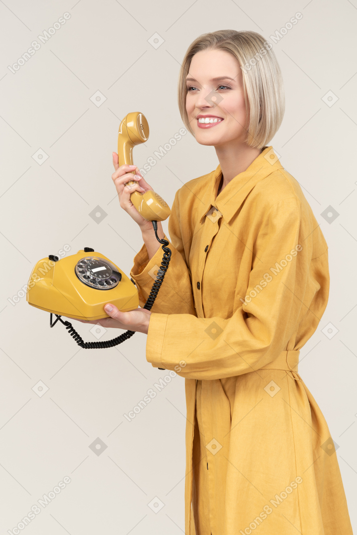Young woman holding old rotary phone's handset