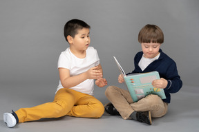 Verärgerter asiatischer junge, der versucht, buch mit seinem freund zu lesen