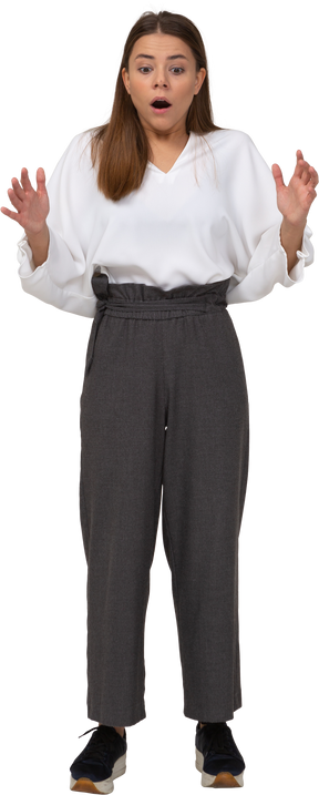 Front view of a shocked young lady in office clothing raising hands