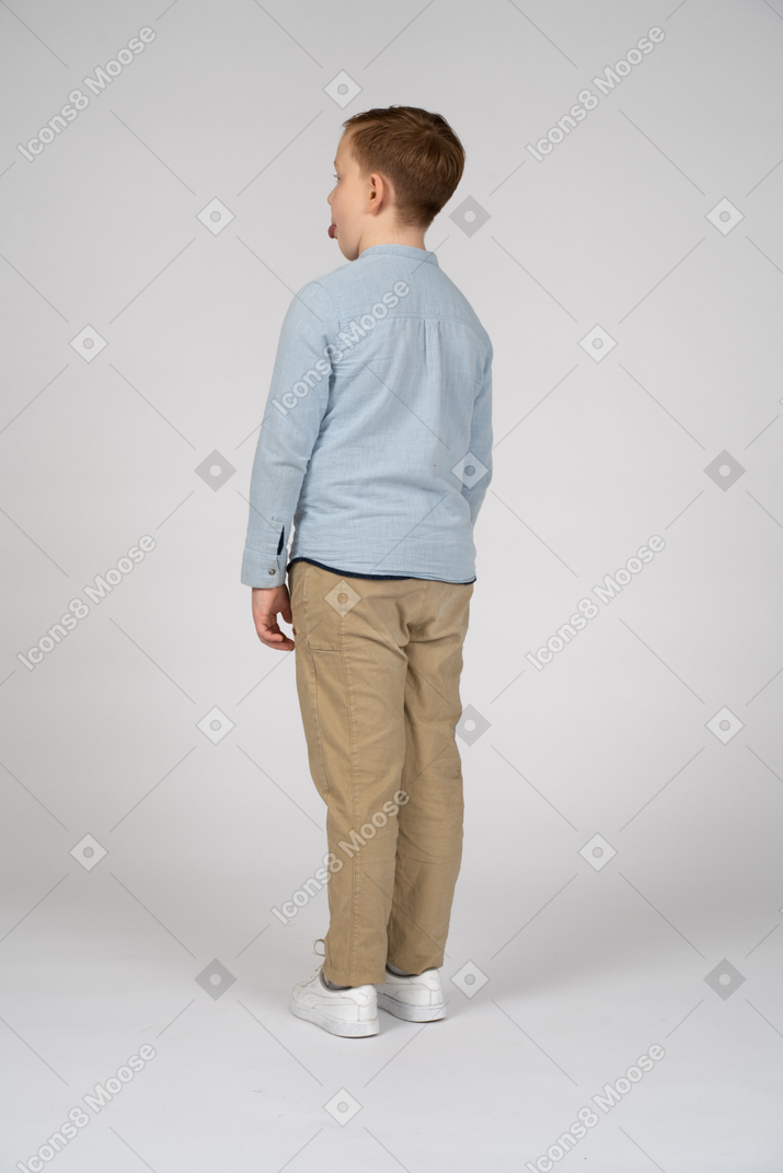 Rear view of a boy in casual clothes showing tongue