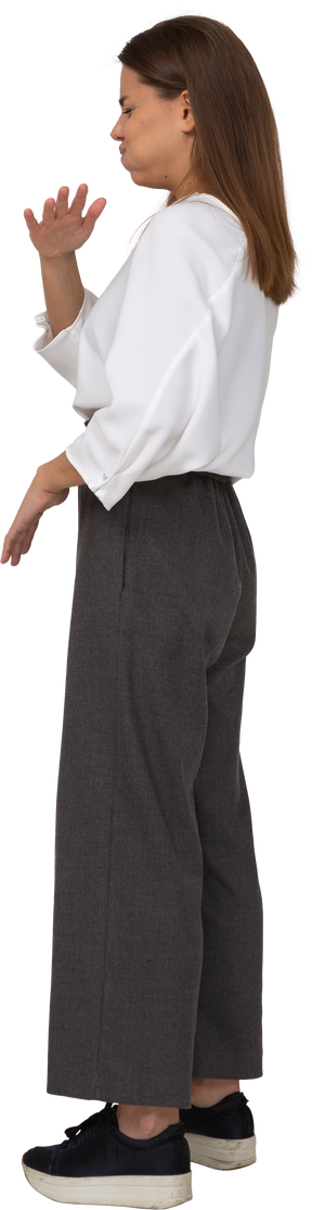Side view of a displeased young lady in office clothing waving hand