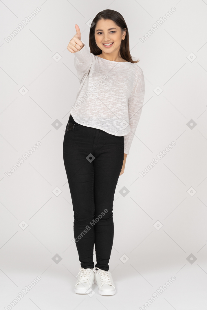 Vista frontal de una joven mujer india en ropa casual mostrando el pulgar hacia arriba