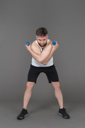 Hombre deportivo haciendo ejercicios de brazo con pesas azules