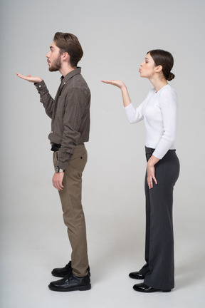 Side view of a young couple in office clothing sending an air kiss