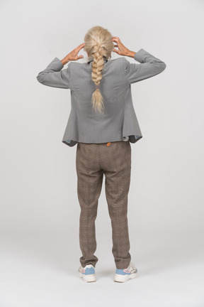 Back view of an old lady in suit touching head