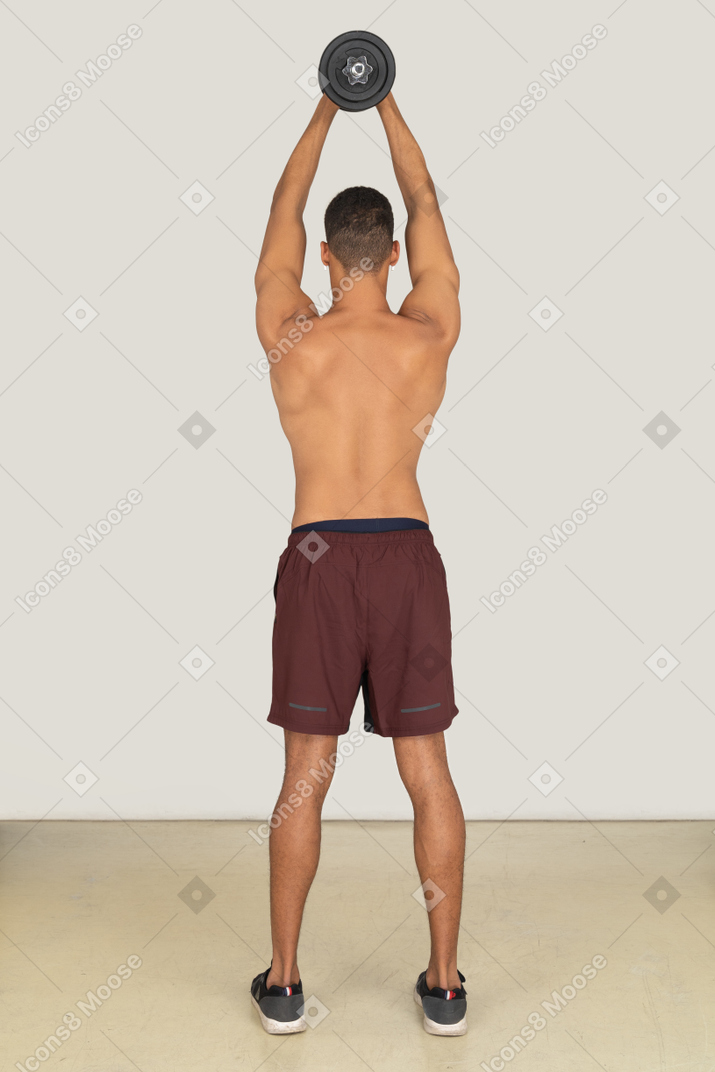 Вид сзади на мускулистого мужчину, держащего гантель