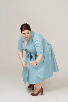Front view of a woman in blue dress squatting