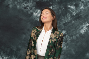 Uma mulher com uma jaqueta verde japonesa sorri com os olhos fechados