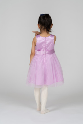 Back view of  a little girl in a tutu dress pointing left