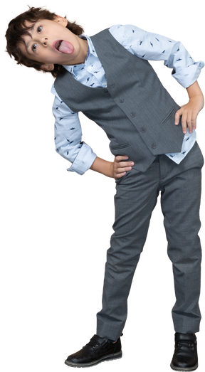 Vista frontale di un ragazzo in abito grigio in posa con le mani sui fianchi e lingua showin