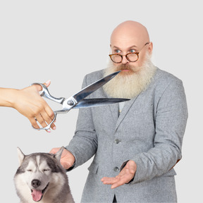 Surprised bearded man, huge scissors and happy dog