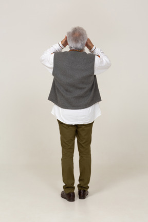 Rear view of a man in gray vest covering his eyes