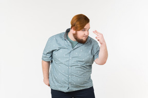 A fat man pointing two v-sign fingers at his eyes