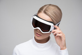 Young blonde woman adjusting her ski goggles
