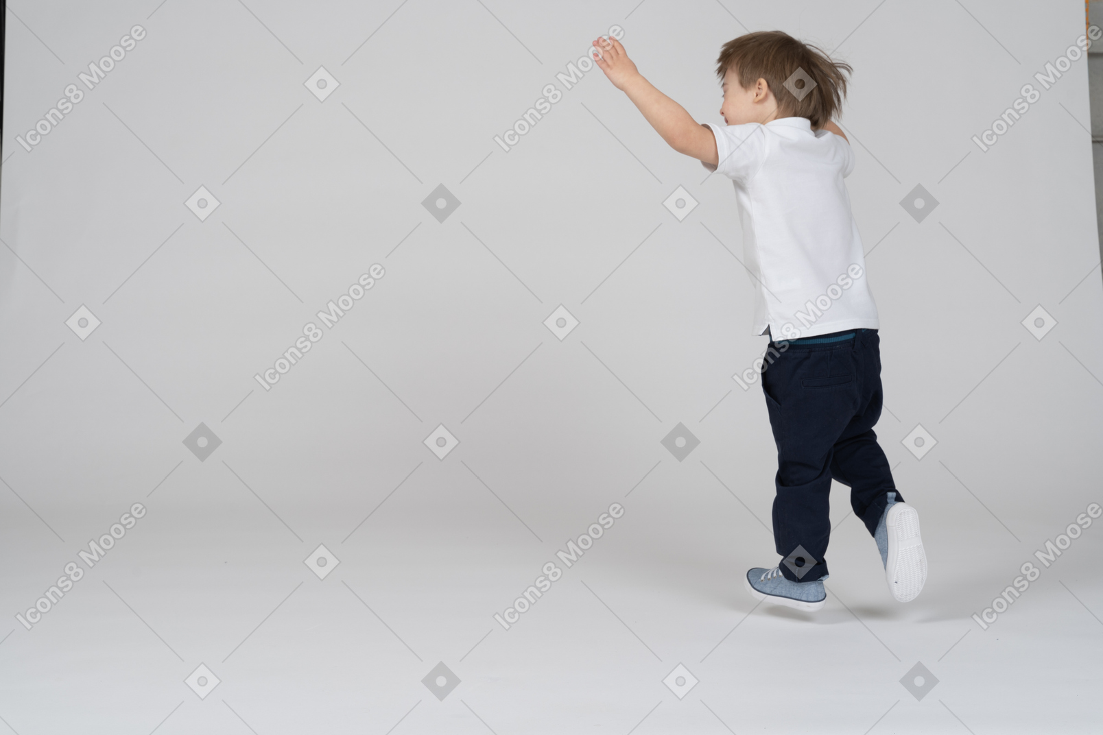 Back view of a boy running with hands raised