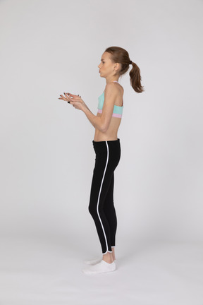 Side view of a teen girl in sportswear raising hand and arguing