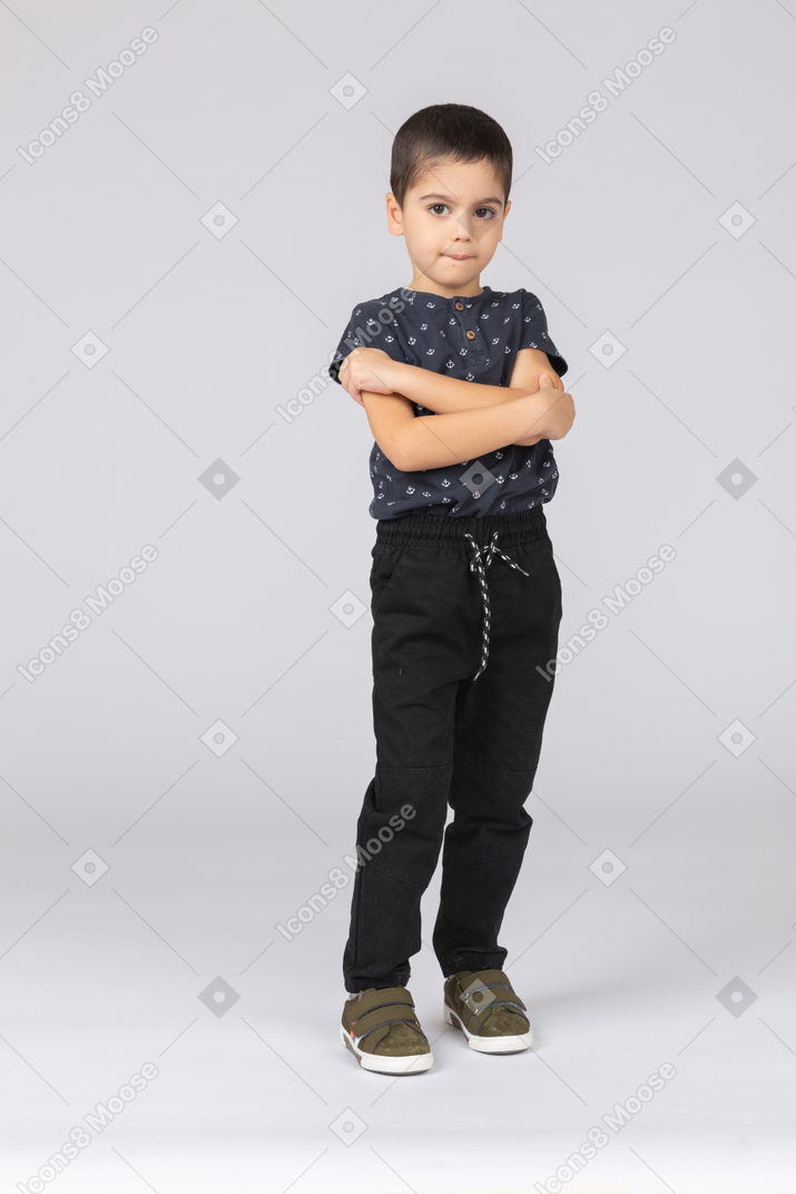 Vista frontal de un chico lindo posando con los brazos cruzados y mirando a la cámara