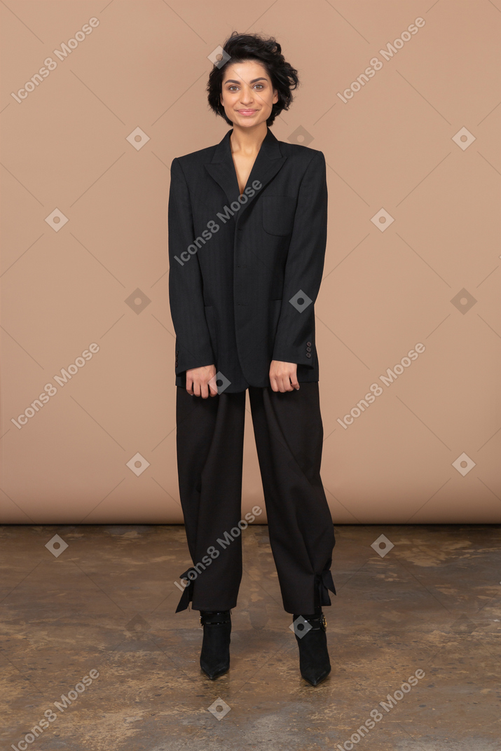 Vista frontal de uma empresária em um terno preto olhando alegremente para a câmera