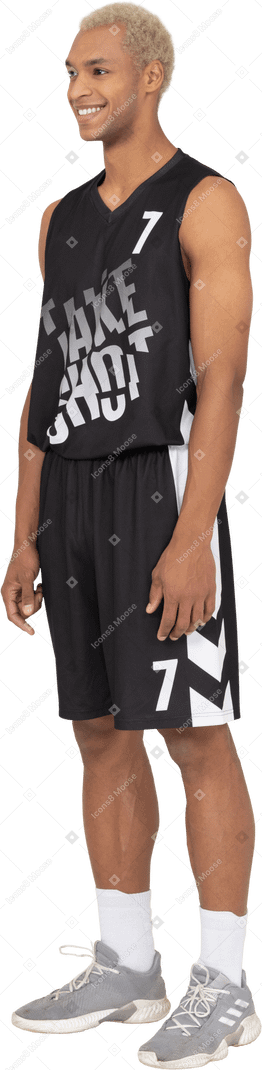 一个微笑的年轻男篮球运动员站着不动的四分之三视图