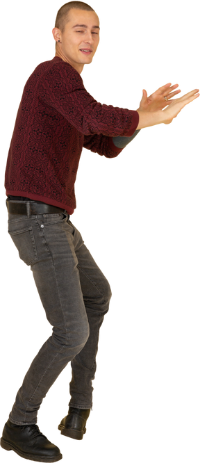 Вид спереди на молодого человека в красном пуловере, протягивающего руки