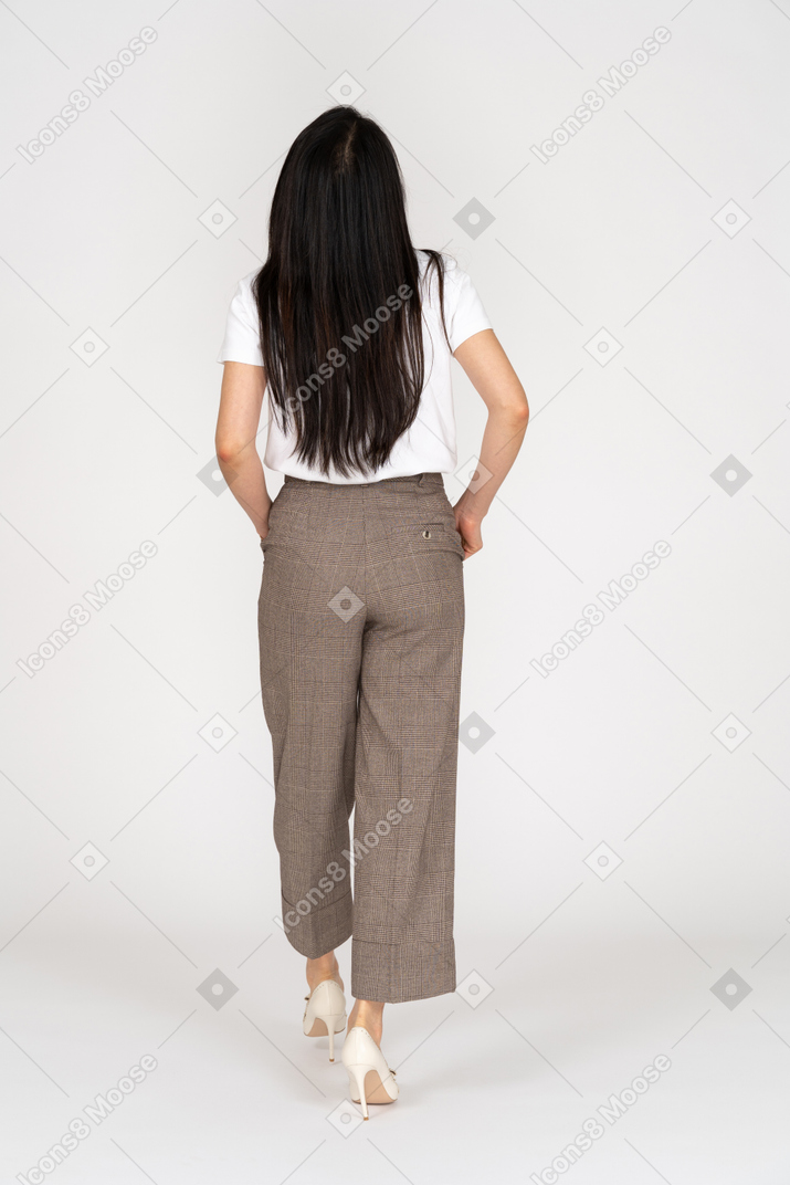 Rückansicht einer wandelnden jungen dame in reithose und t-shirt