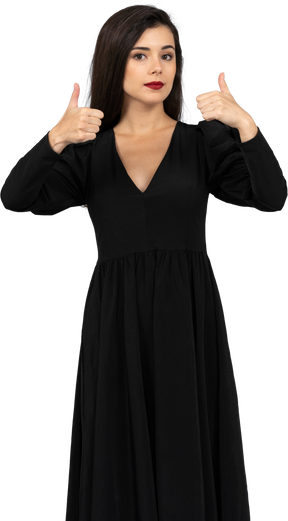 Vista frontal de uma jovem em um vestido preto mostrando os polegares para cima