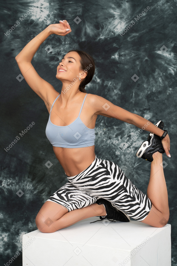 Atleta feminina esticando os quadris, levantando o braço e sorrindo