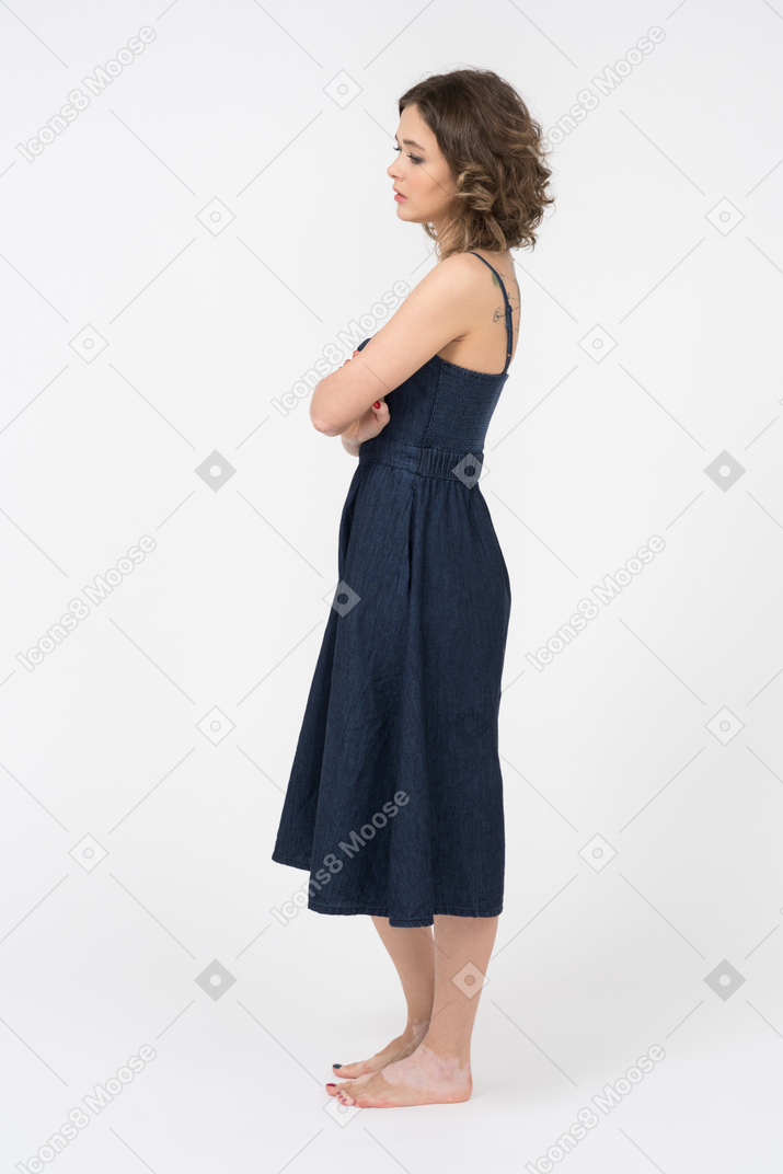 Triste donna bruna in piedi di profilo con le braccia incrociate