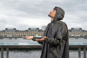 A man in a raincoat standing on a pier