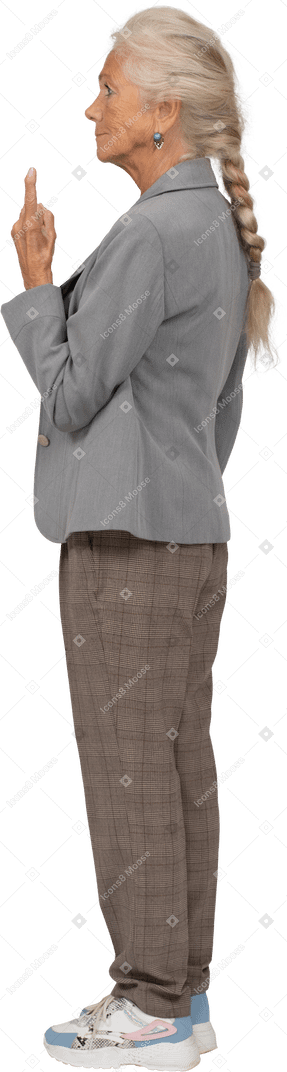 Seitenansicht einer alten dame im anzug, die mit einem finger nach oben zeigt