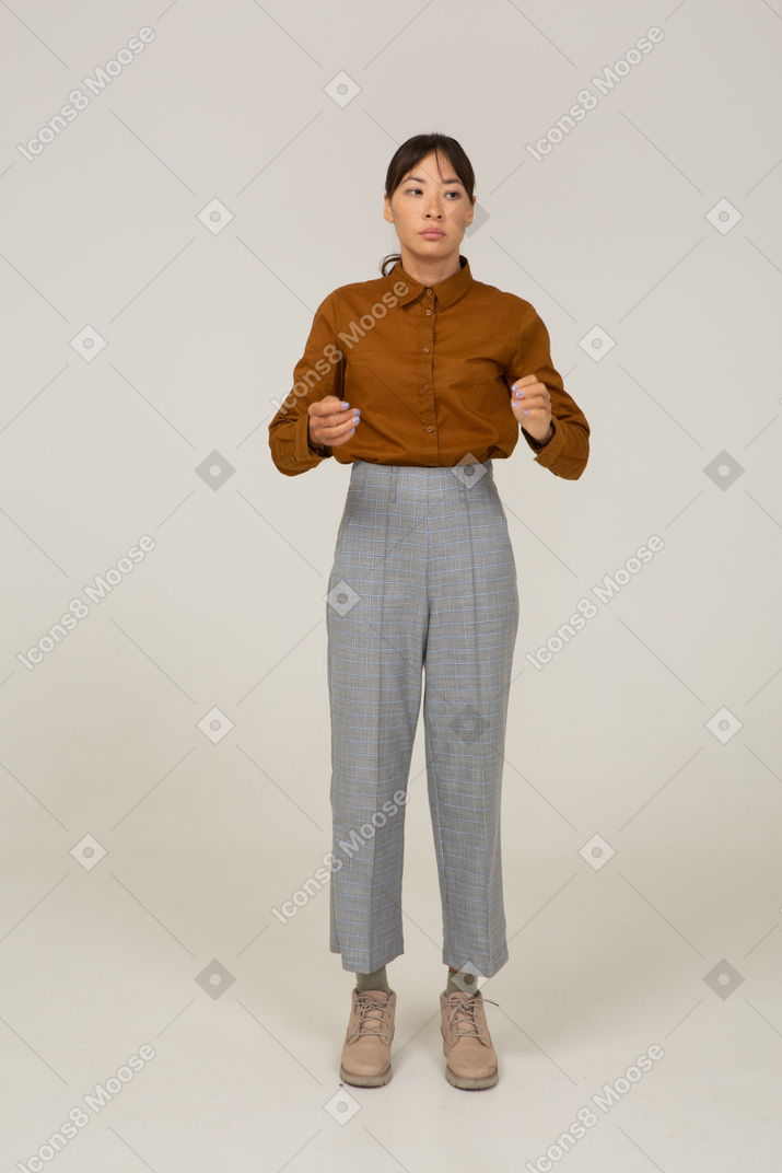 Vista frontal de una joven mujer asiática en calzones y blusa levantando sus manos