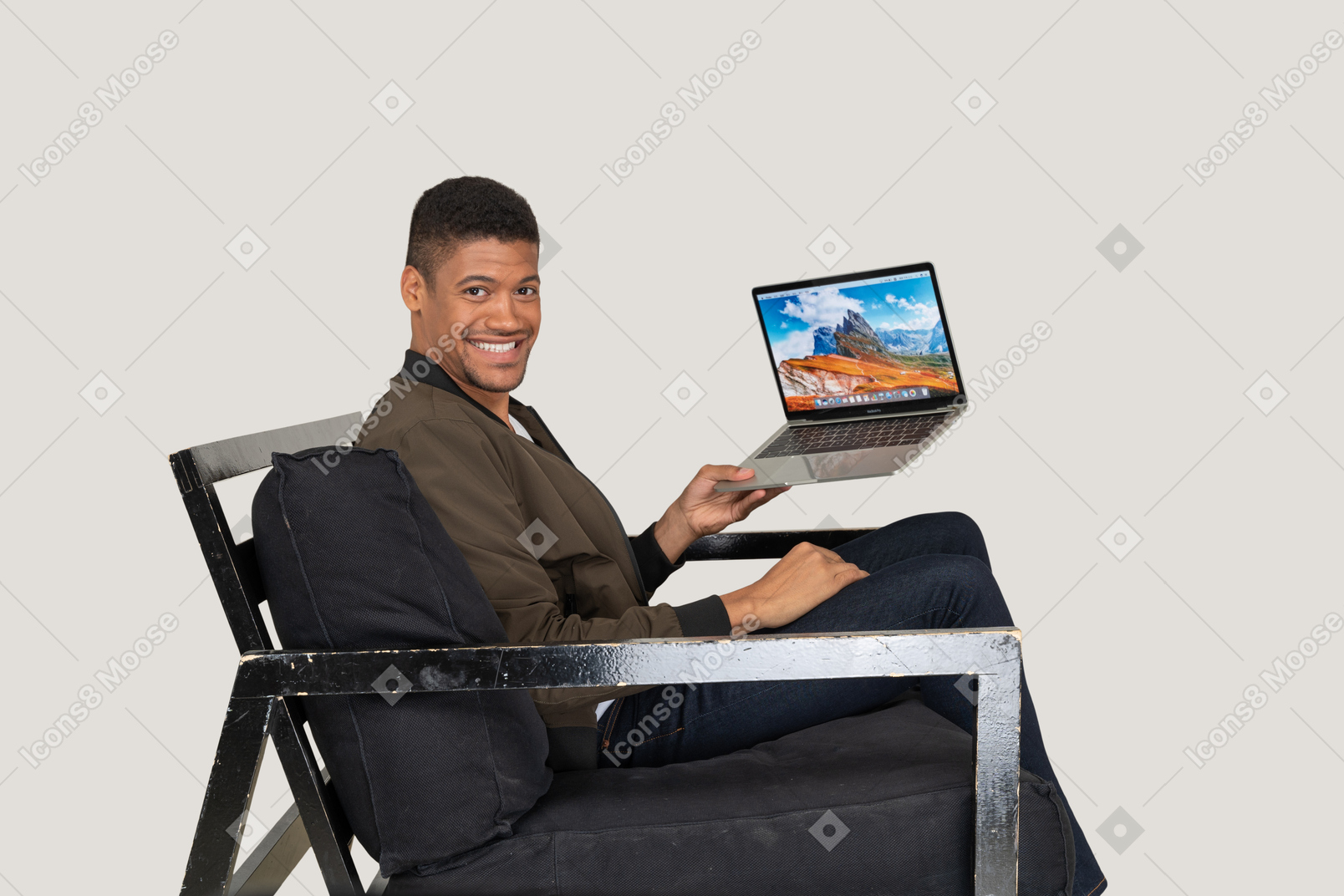 坐在沙发上拿着笔记本电脑的年轻人的侧视图