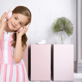 A little girl in a pink dress listening to headphones