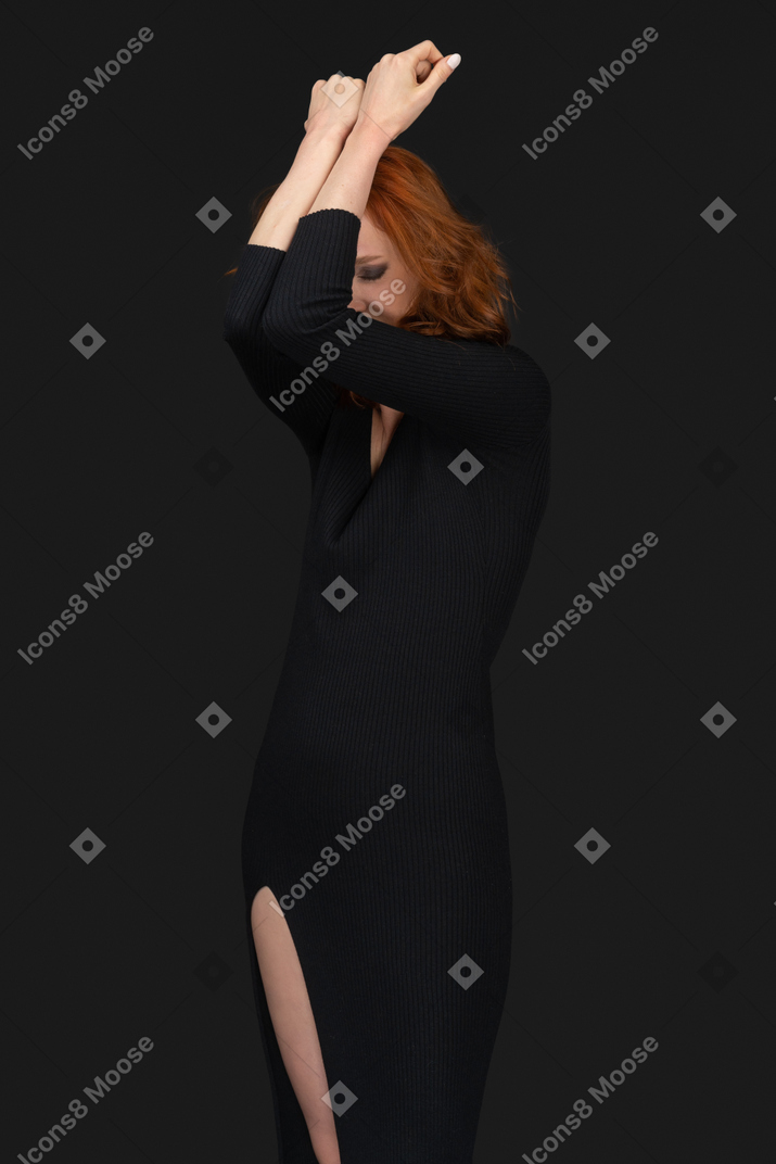A frontal view of the sexy young woman dressed in black and covering her face with hands