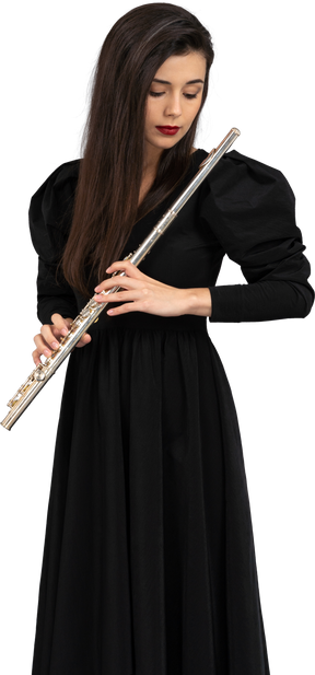 Vista frontal de uma jovem séria de vestido preto segurando uma flauta