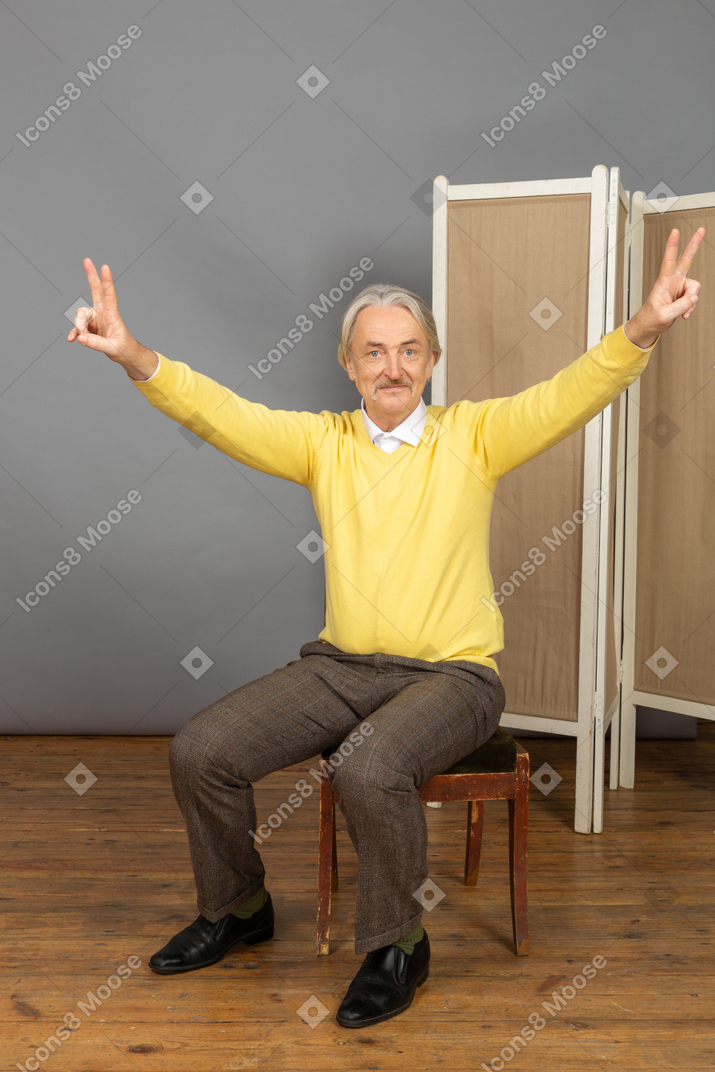 Man sitting on chair and showing peace sign