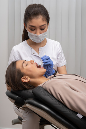 Dentista femminile esaminando il suo paziente femminile spaventato sulla sedia medica