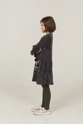 Side view of an offended little girl in dress crossing arms