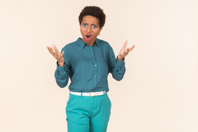 Mujer negra con un corte de pelo corto, vestida de azul, de pie contra un fondo pastel liso, con aspecto emocional